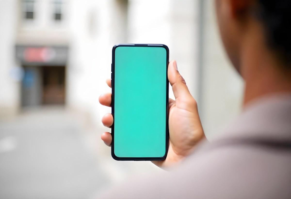 Black Man Holding A Smartphone With A Blank Turquoise Screen The Background Is A Blurred City Street 7 4c60