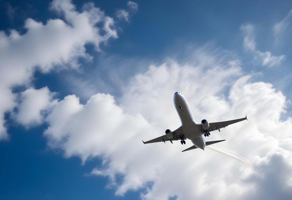 An Airplane Flying Against A Backdrop Of Blue Sky With Scattered Clouds The Aircraft Is Viewed From Below Showcasing Its Wings And Tail 25 7339