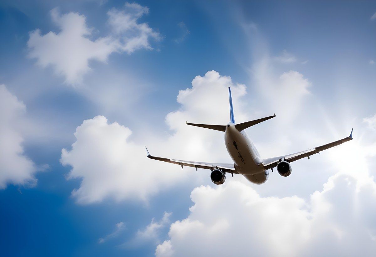 An Airplane Flying Against A Backdrop Of Blue Sky With Scattered Clouds The Aircraft Is Viewed From Below Showcasing Its Wings And Tail 3 16b2