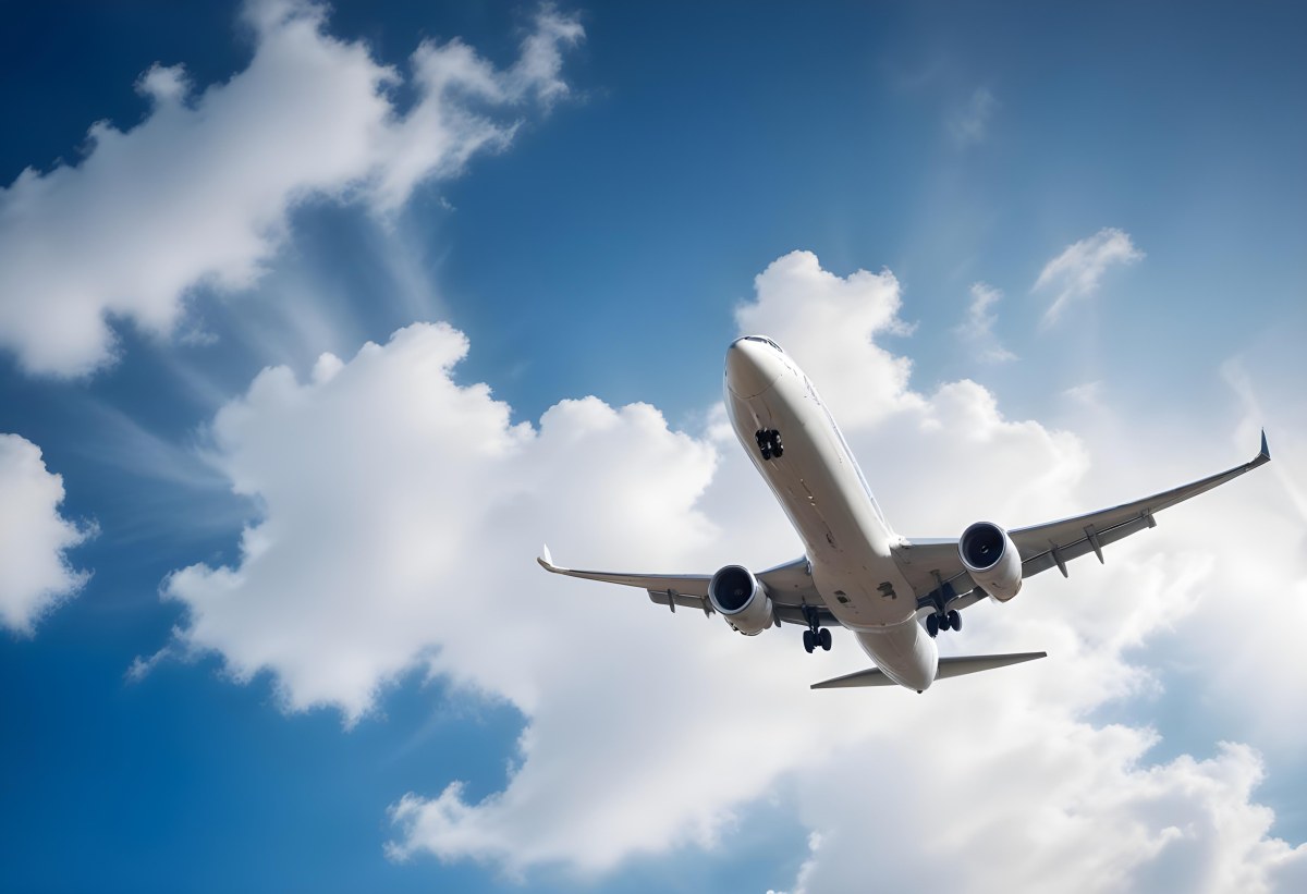 An Airplane Flying Against A Backdrop Of Blue Sky With Scattered Clouds The Aircraft Is Viewed From Below Showcasing Its Wings And Tail 6 1239