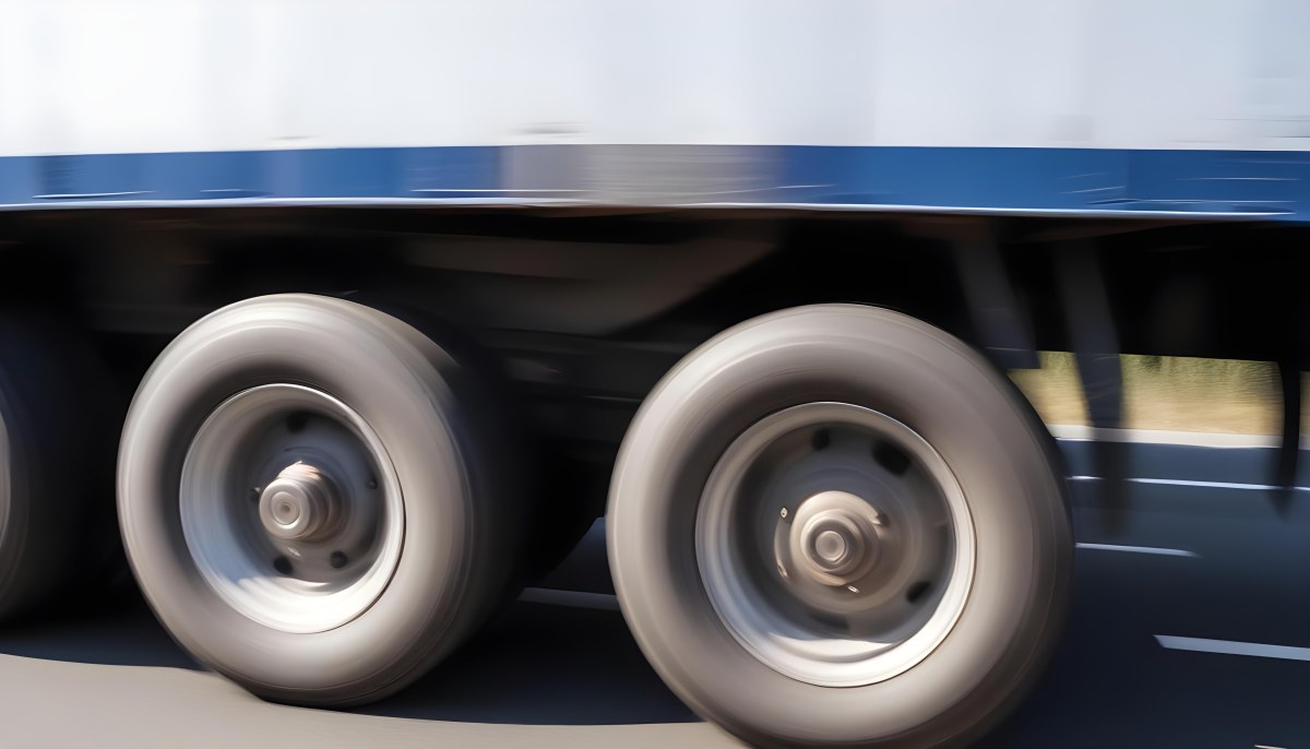 Truck Wheels In Motion Showing The Blur Of Movement With A Blue And White Truck Body Above On A Road 1 Db16