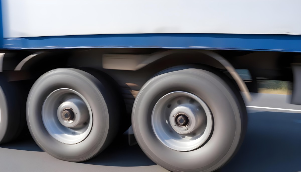 Truck Wheels In Motion Showing The Blur Of Movement With A Blue And White Truck Body Above On A Road 2 3a1c