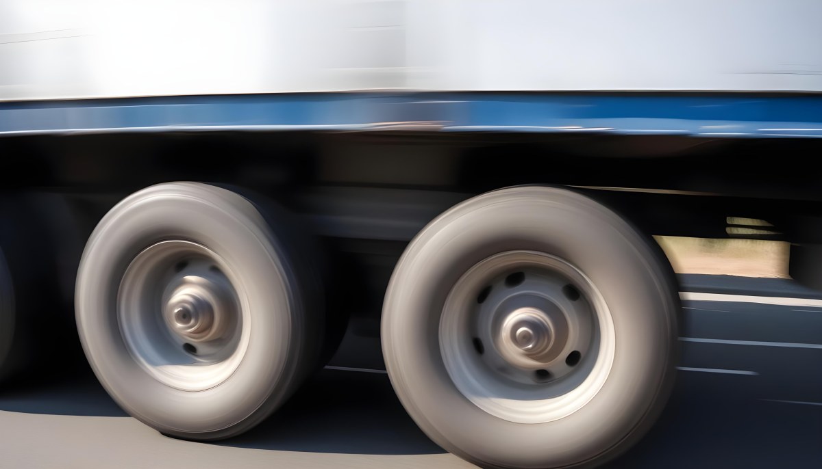 Truck Wheels In Motion Showing The Blur Of Movement With A Blue And White Truck Body Above On A Road 4 A5cb