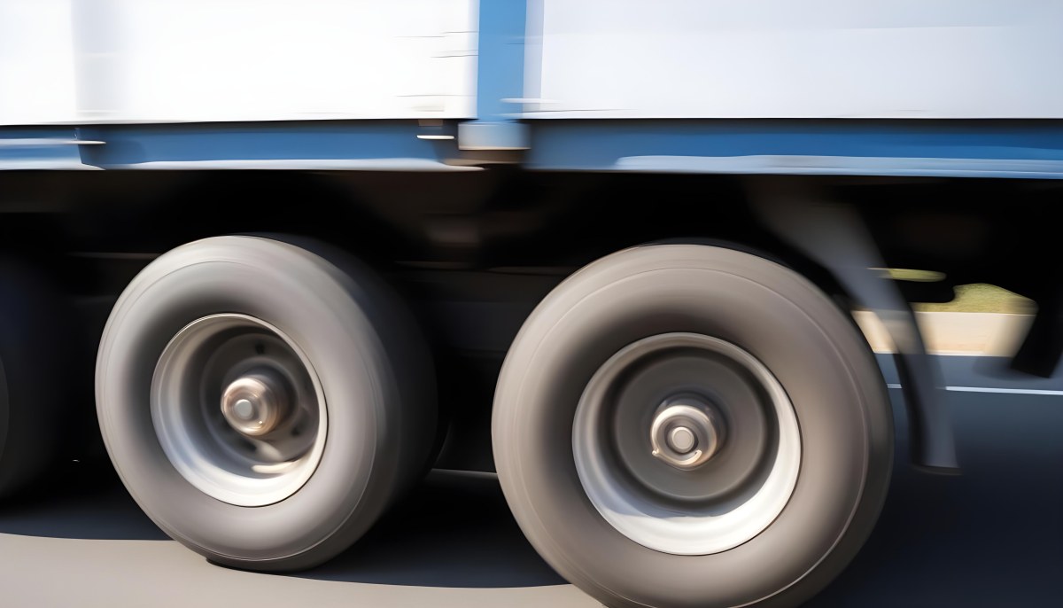 Truck Wheels In Motion Showing The Blur Of Movement With A Blue And White Truck Body Above On A Road 6 7868