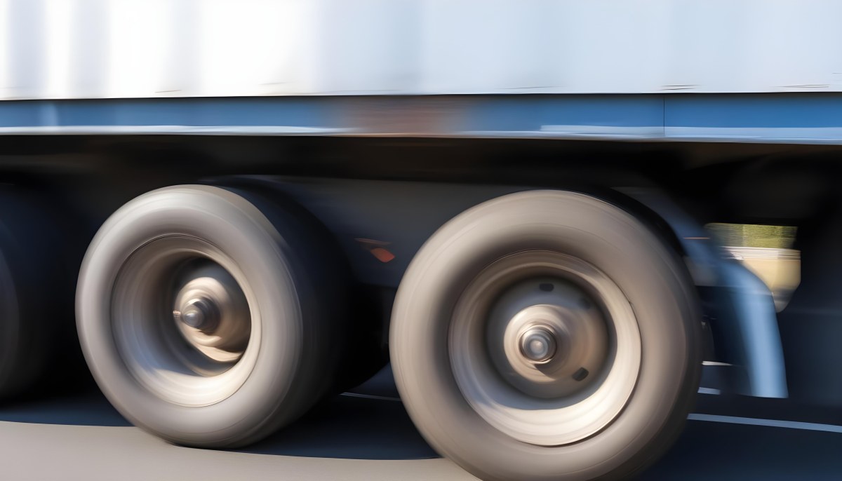 Truck Wheels In Motion Showing The Blur Of Movement With A Blue And White Truck Body Above On A Road 8 6765