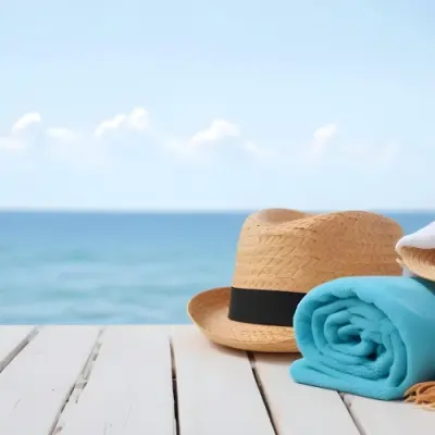 A Straw Hat And A White Towel On A White Wooden Table With A Blurred Background Of The Sea And The Sky 15 B641