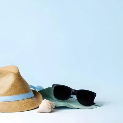 A Straw Hat With A Blue Ribbon Black Sunglasses A Seashell And A Seashell On A White Surface With A Light Blue Background 10 9015