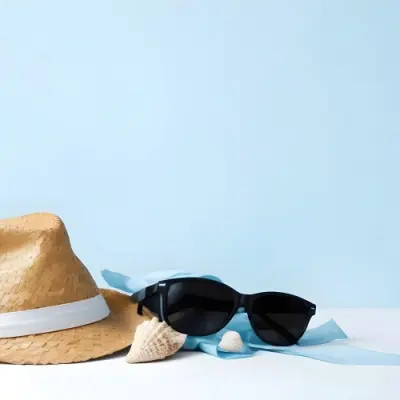 A Straw Hat With A Blue Ribbon Black Sunglasses A Seashell And A Seashell On A White Surface With A Light Blue Background 11 Ba86