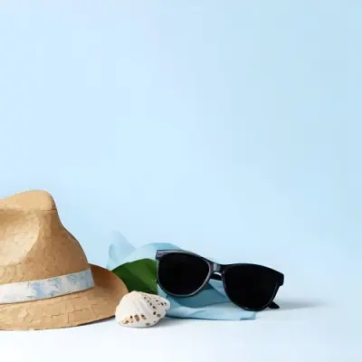 A Straw Hat With A Blue Ribbon Black Sunglasses A Seashell And A Seashell On A White Surface With A Light Blue Background 12 D08a