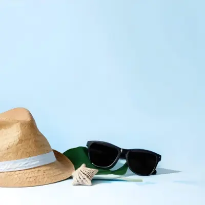 A Straw Hat With A Blue Ribbon Black Sunglasses A Seashell And A Seashell On A White Surface With A Light Blue Background 3 D291