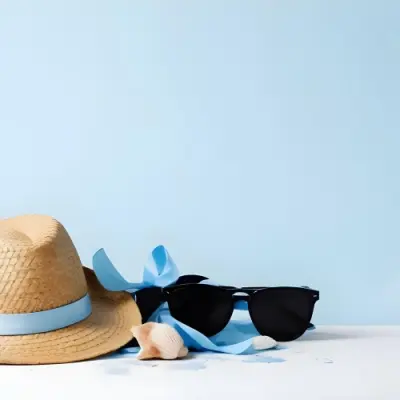 A Straw Hat With A Blue Ribbon Black Sunglasses A Seashell And A Seashell On A White Surface With A Light Blue Background 4 Bf13