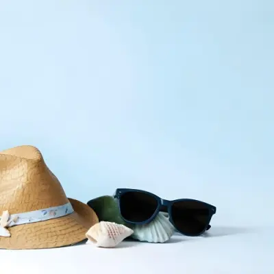 A Straw Hat With A Blue Ribbon Black Sunglasses A Seashell And A Seashell On A White Surface With A Light Blue Background 6 A21a