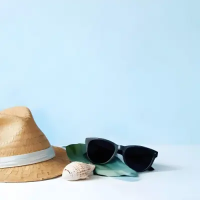 A Straw Hat With A Blue Ribbon Black Sunglasses A Seashell And A Seashell On A White Surface With A Light Blue Background 9 38d6