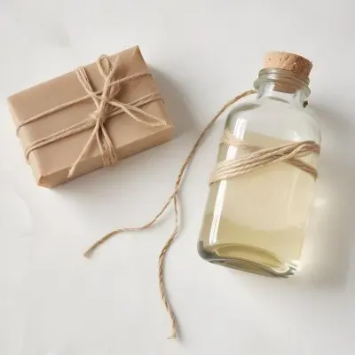 A Bar Of Soap Tied With Twine And A Clear Glass Bottle With A White Cap On A White Textured Surface 26 858b