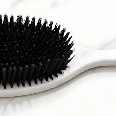 A Black Hair Brush With White Bristles Placed On A Marble Countertop 2 2b09