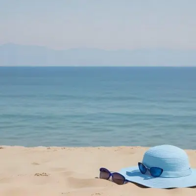 A Blue Sun Hat And Blue Sunglasses On A Sandy Beach With A Blue Sea And Sky In The Background 22 20bd