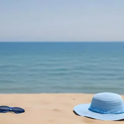 A Blue Sun Hat And Blue Sunglasses On A Sandy Beach With A Blue Sea And Sky In The Background 32 A07e