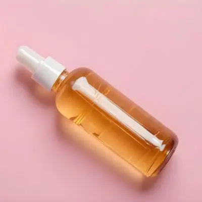 A Bottle Of Hair Oil And A Strand Of Blonde Hair On A Pink Background 12 Ce3c