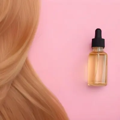 A Bottle Of Hair Oil And A Strand Of Blonde Hair On A Pink Background 29 F6f4