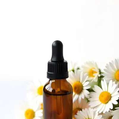 A Bottle Of Yellow Liquid Surrounded By White Daisy Flowers On A Light Background 15 5857
