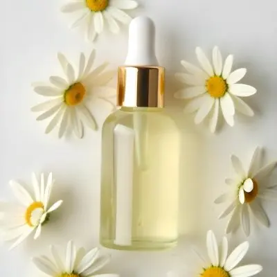 A Bottle Of Yellow Liquid Surrounded By White Daisy Flowers On A Light Background 16 B327