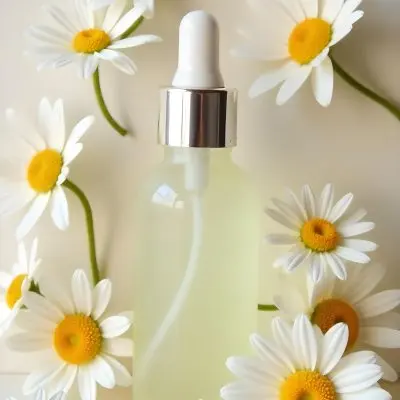 A Bottle Of Yellow Liquid Surrounded By White Daisy Flowers On A Light Background 2 A730