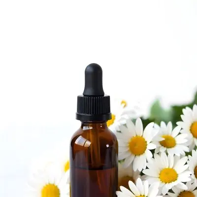 A Bottle Of Yellow Liquid Surrounded By White Daisy Flowers On A Light Background 26 9f6c