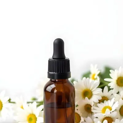A Bottle Of Yellow Liquid Surrounded By White Daisy Flowers On A Light Background 31 88e3