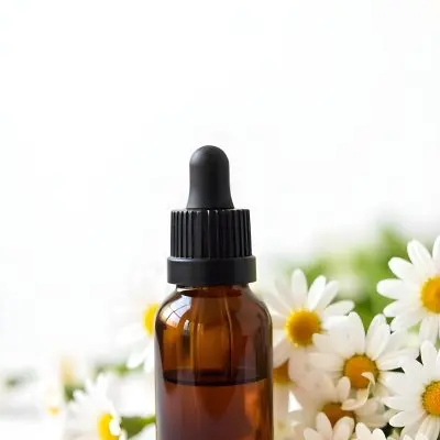 A Bottle Of Yellow Liquid Surrounded By White Daisy Flowers On A Light Background 33 A1a7