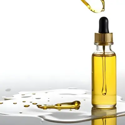 A Bottle Of Yellow Oil With A Dropper A Splash Of Oil On A White Surface And A White Background 12 14ca