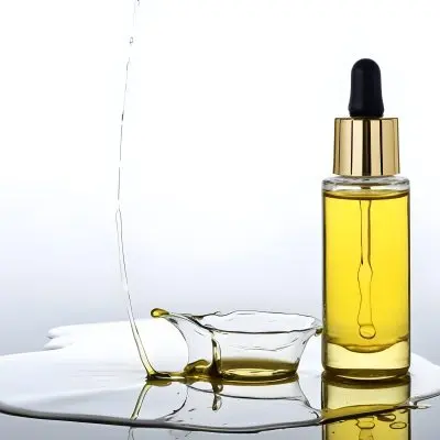 A Bottle Of Yellow Oil With A Dropper A Splash Of Oil On A White Surface And A White Background 16 Edc5