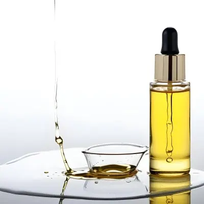A Bottle Of Yellow Oil With A Dropper A Splash Of Oil On A White Surface And A White Background 20 548e