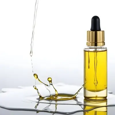 A Bottle Of Yellow Oil With A Dropper A Splash Of Oil On A White Surface And A White Background 24 832a
