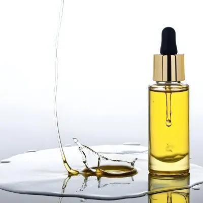 A Bottle Of Yellow Oil With A Dropper A Splash Of Oil On A White Surface And A White Background 4 D702