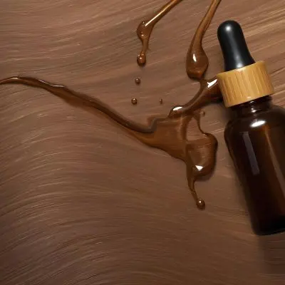 A Brown Glass Bottle With A Dropper On A Background Of Brown Hair The Hair Is Wavy And Shiny The Bottle Is In The Upper Right Corner 26 Bc14