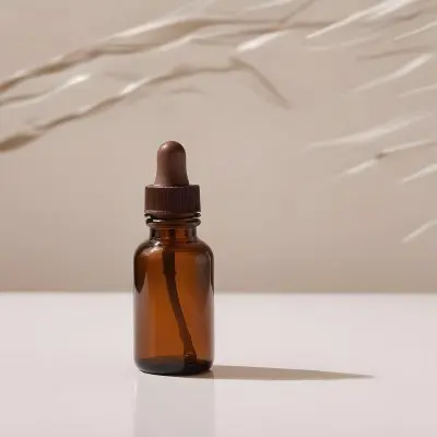 A Brown Glass Bottle With A Dropper On A White Surface With Brown Wavy Hair In The Background 3 1c21