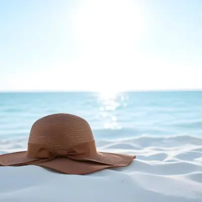 A Brown Sun Hat With A Ribbon On A White Sand Beach Turquoise Sea And Clear Sky In The Background 22 230c
