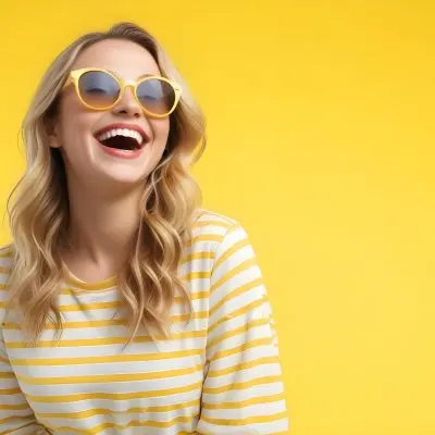 A Caucasian Woman 28 Years Old Blonde Wavy Hair Yellow Sunglasses And A Striped Shirt Laughing In A Yellow Background 19 262b