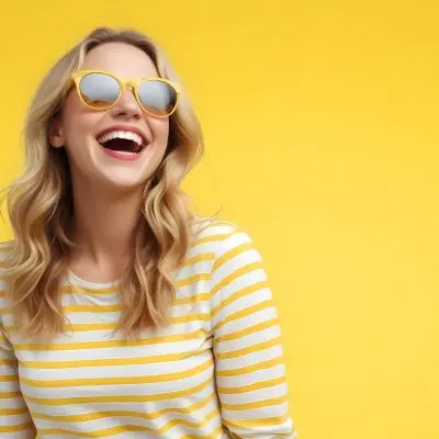 A Caucasian Woman 28 Years Old Blonde Wavy Hair Yellow Sunglasses And A Striped Shirt Laughing In A Yellow Background 5 6605
