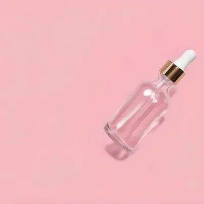A Clear Glass Bottle With A Dropper Cap Filled With A Clear Liquid Placed Diagonally On A Plain Pink Background 49 Ab7c