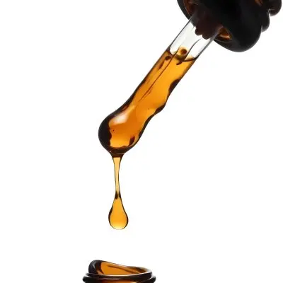 A Close Up Of A Dropper Filled With Amber Liquid Poised Above A Brown Glass Bottle Against A Stark White Background 1 7895