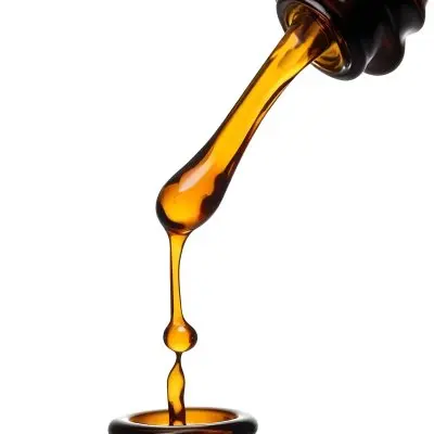 A Close Up Of A Dropper Filled With Amber Liquid Poised Above A Brown Glass Bottle Against A Stark White Background 11 F8a9