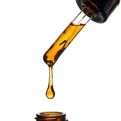 A Close Up Of A Dropper Filled With Amber Liquid Poised Above A Brown Glass Bottle Against A Stark White Background 21 7fed