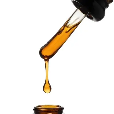 A Close Up Of A Dropper Filled With Amber Liquid Poised Above A Brown Glass Bottle Against A Stark White Background 28 F3d3