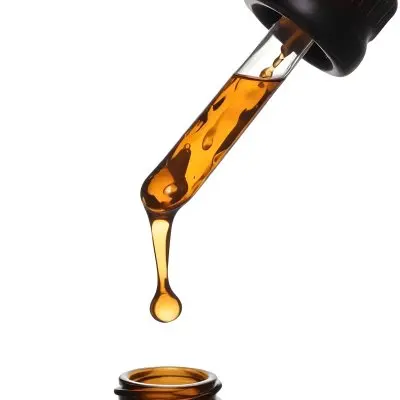 A Close Up Of A Dropper Filled With Amber Liquid Poised Above A Brown Glass Bottle Against A Stark White Background 33 A806