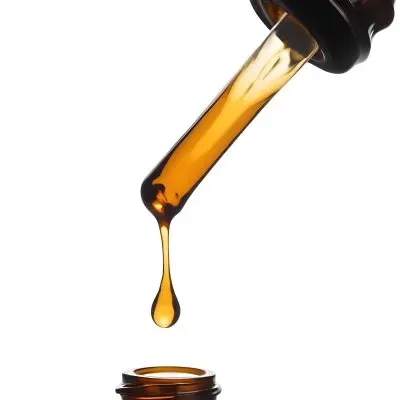 A Close Up Of A Dropper Filled With Amber Liquid Poised Above A Brown Glass Bottle Against A Stark White Background 36 4c34