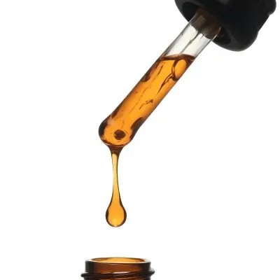 A Close Up Of A Dropper Filled With Amber Liquid Poised Above A Brown Glass Bottle Against A Stark White Background 37 663e