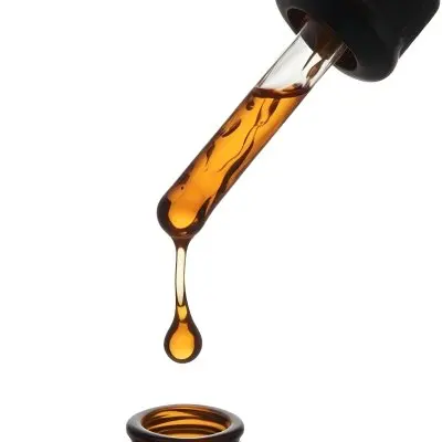 A Close Up Of A Dropper Filled With Amber Liquid Poised Above A Brown Glass Bottle Against A Stark White Background 38 B837