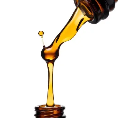 A Close Up Of A Dropper Filled With Amber Liquid Poised Above A Brown Glass Bottle Against A Stark White Background 6 962d