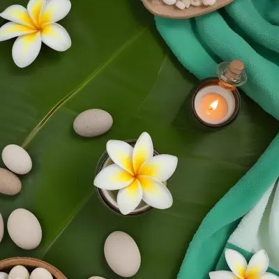 A Frangipani Flower A Candle Stones And A Jar Of Oil On A Green Leaf Background With A Green Towel In The Upper Right Corner 27 0be1